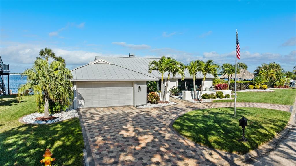 A single-story house with a metal roof and paver driveway sits near the water — 5791 WESTSHORE DRIVE, NEW PORT RICHEY, FL