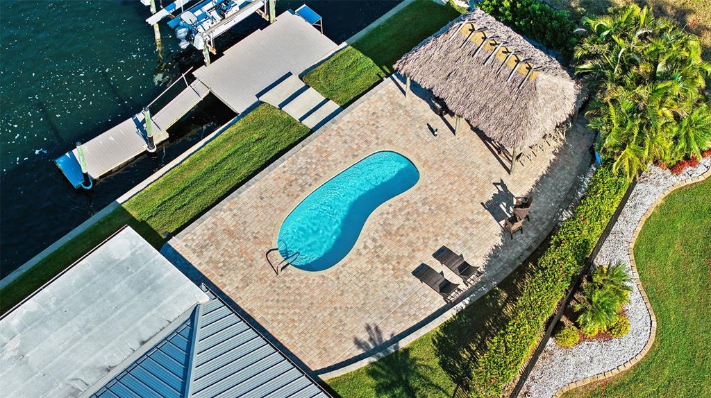 An aerial view shows a backyard with a kidney-shaped pool, tiki hut, and boat dock — 5791 WESTSHORE DRIVE, NEW PORT RICHEY, FL