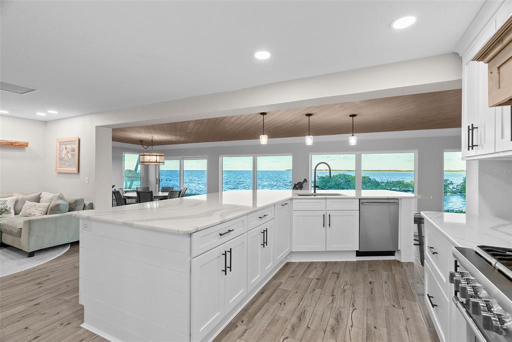 A modern kitchen with white cabinets and a large island overlooks a waterfront view — 5791 WESTSHORE DRIVE, NEW PORT RICHEY, FL