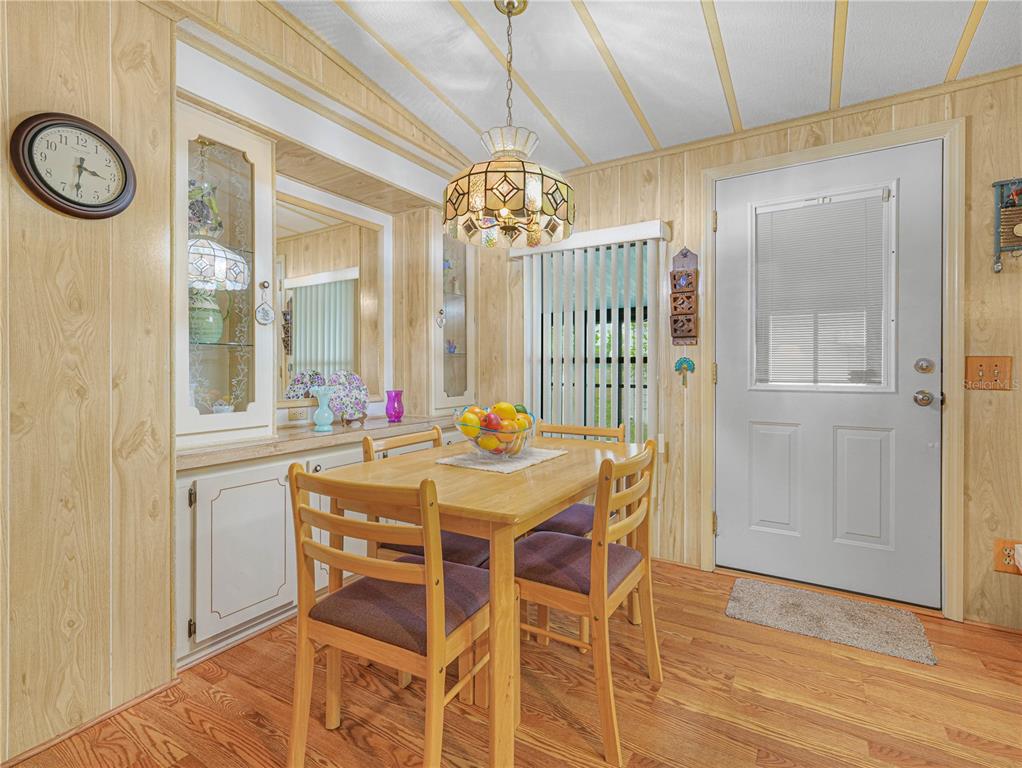 A dining area features wood-paneled walls, a wooden table with four chairs, and a glass door — 108 KENSINGTON PARK DRIVE, DAVENPORT, FL