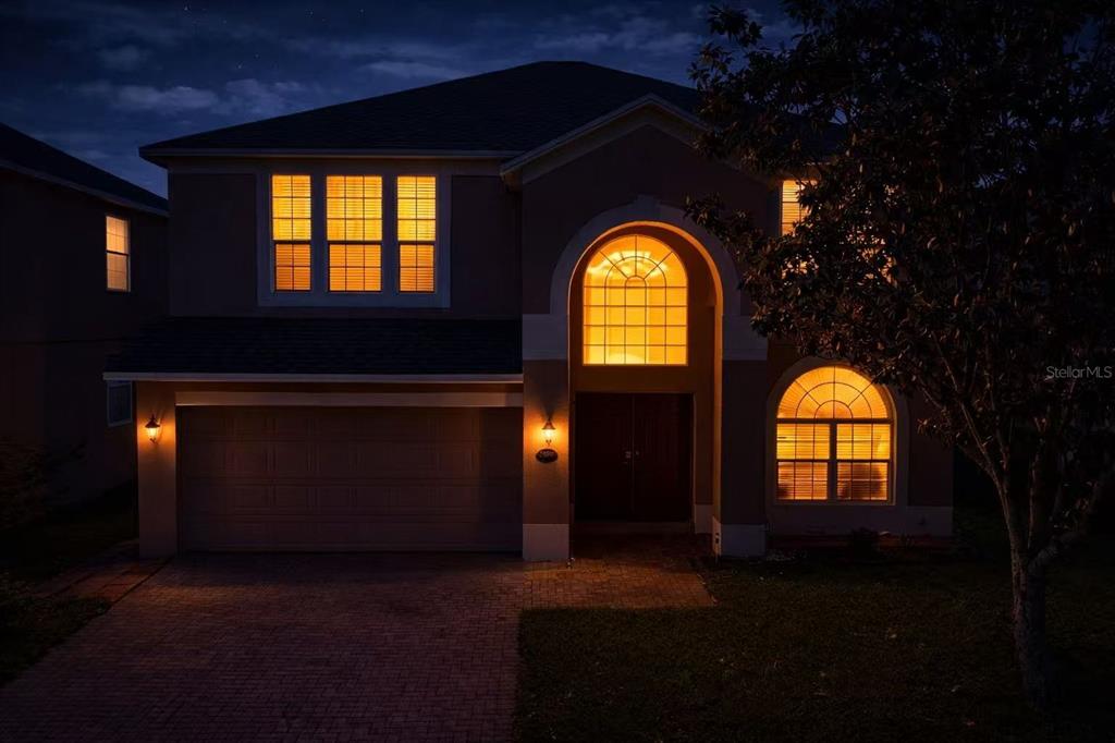 A two-story house exterior at night with illuminated windows and a paved driveway — 13212 SOCIAL LANE, WINTER GARDEN, FL