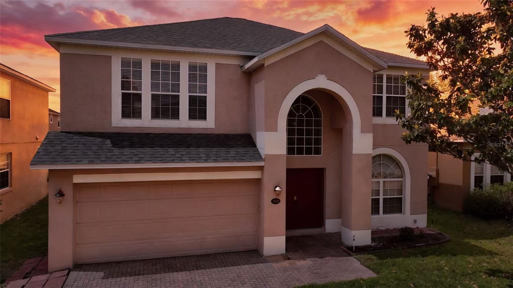 A two-story suburban house with a tan stucco exterior, a garage, and an arched entryway — 13212 SOCIAL LANE, WINTER GARDEN, FL