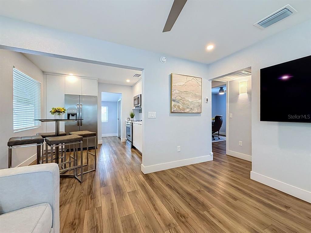 A living room opens into a kitchen with stainless steel appliances and wood-look flooring — 5458 6TH AVENUE N, ST PETERSBURG, FL