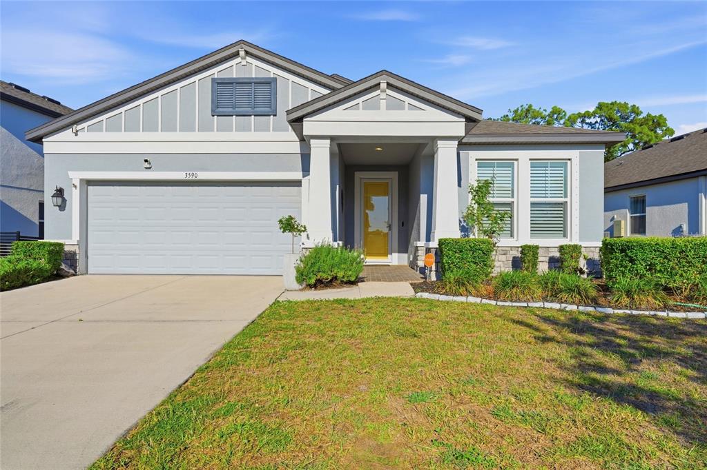 A single-story house features a gray exterior, a two-car garage, and a yellow front door — 3590 SECRET STROLL DRIVE, SARASOTA, FL