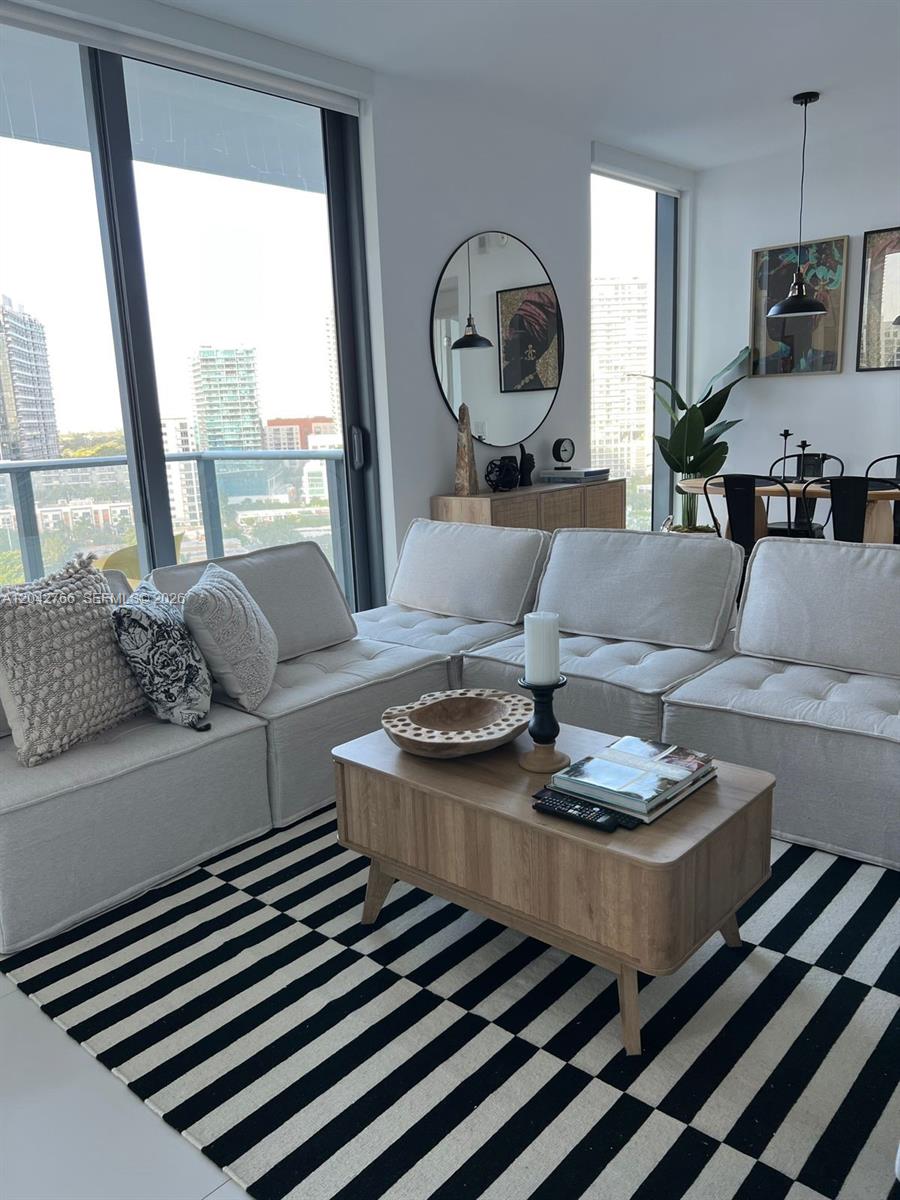 A modern living room features a modular sofa, striped rug, and floor-to-ceiling windows — 501 NE 31st St # 1409, Miami FL 33137, MIAMI, FL