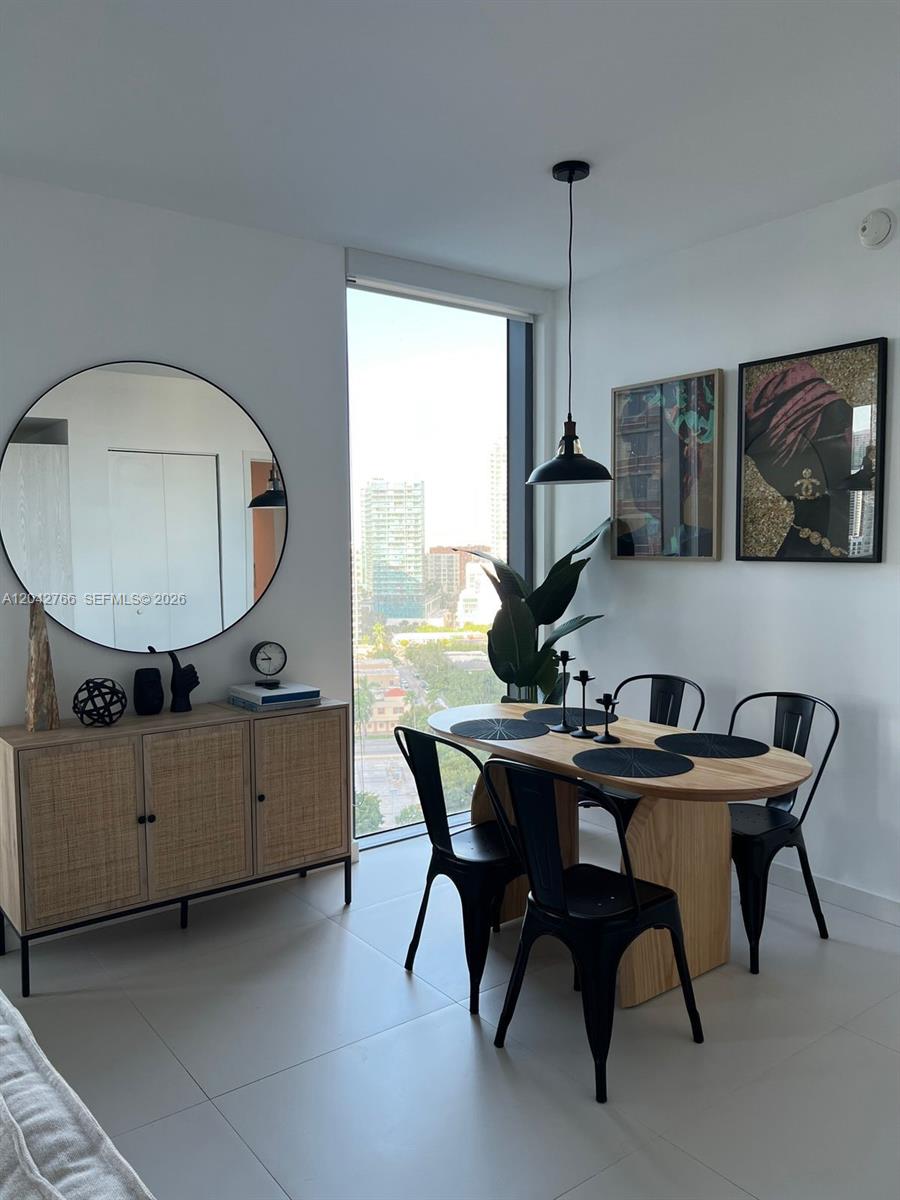 A dining area features a wooden table, black chairs, a sideboard, and a large round mirror — 501 NE 31st St # 1409, Miami FL 33137, MIAMI, FL