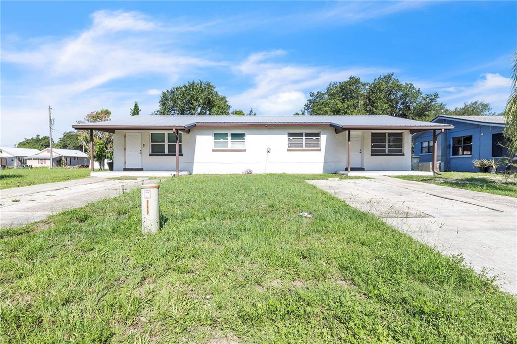 A single-story duplex with a white stucco exterior, metal roof, and two concrete driveways — 311 & 313 N ARCADIA AVENUE, ARCADIA, FL