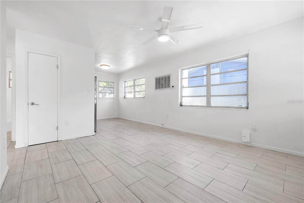 A bright, empty room features white walls, light wood-look tile flooring, and a ceiling fan — 311 & 313 N ARCADIA AVENUE, ARCADIA, FL