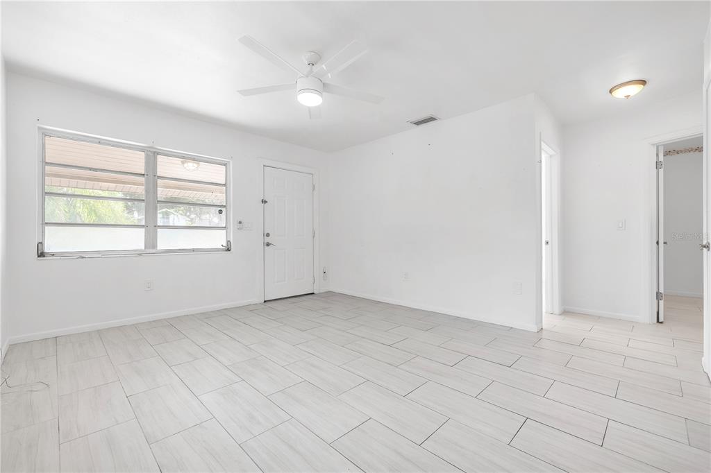 An empty room with white walls, light-colored tile flooring, a ceiling fan, and a door — 311 & 313 N ARCADIA AVENUE, ARCADIA, FL