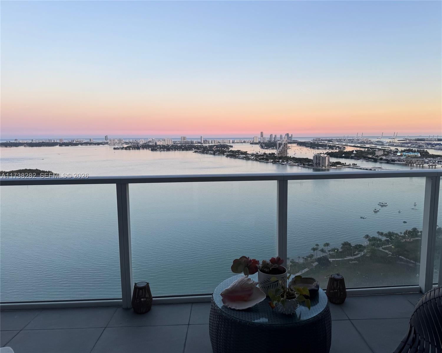 A balcony with a glass railing overlooks a bay and city skyline at sunset — 2020 N Bayshore Dr # 3307, Miami FL 33137, MIAMI, FL