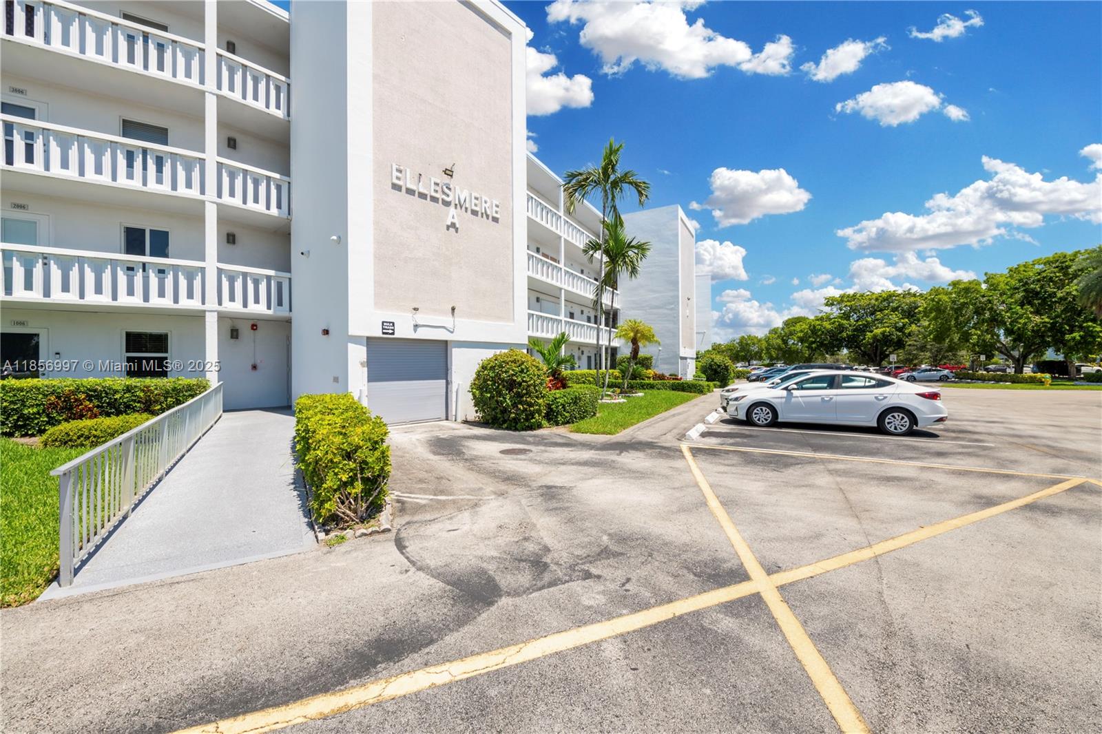 A white multi-story apartment building features a parking lot and a ramped entrance — 1010 Ellesmere A # 1010, Deerfield Beach FL 33442, DEERFIELD BEACH, FL