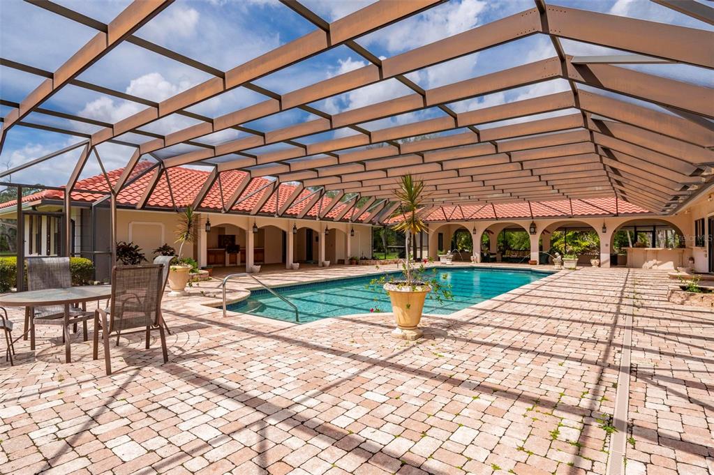 A large swimming pool is enclosed by a screened lanai with brick pavers and arches — 1105 YORKSHIRE STREET, PORT CHARLOTTE, FL