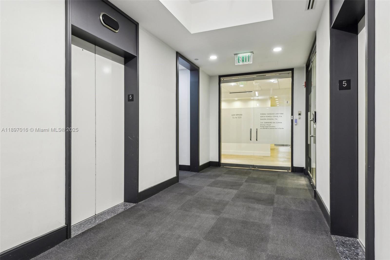 A hallway features an elevator, a glass-fronted office entrance, and gray carpeted flooring — 1200 Brickell Ave # D, Miami FL 33131, MIAMI, FL