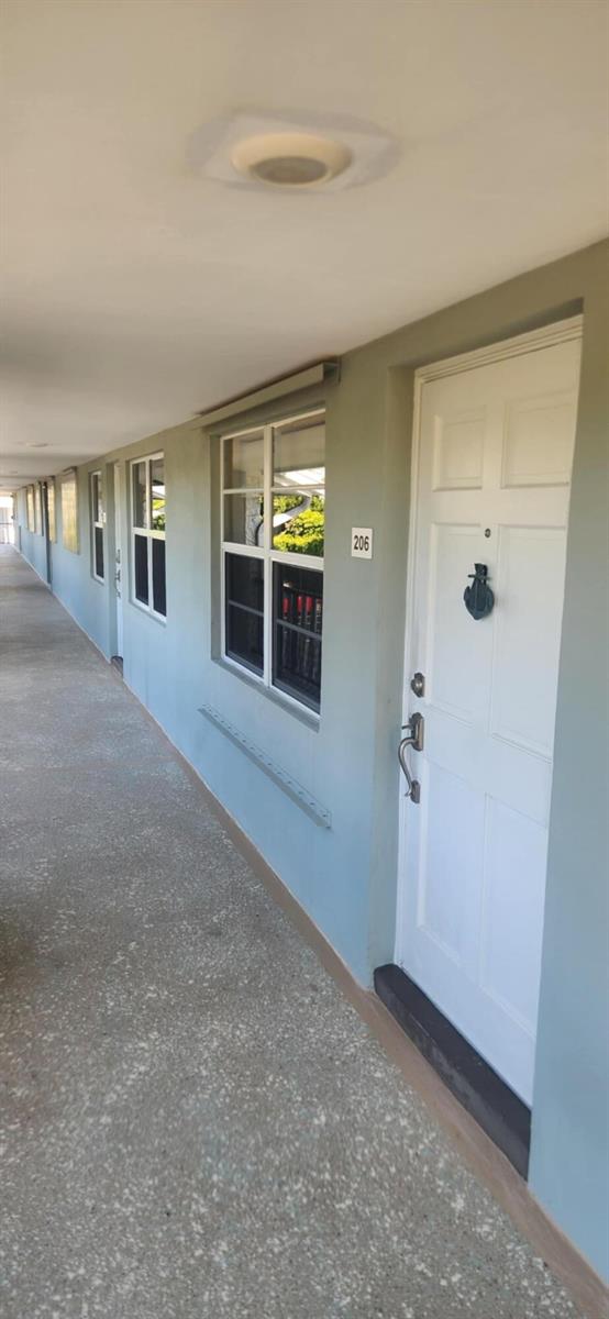 An exterior view of an apartment building hallway with a white door labeled 206 — 5510 N Ocean # 206, Ocean Ridge FL 33435, OCEAN RIDGE, FL
