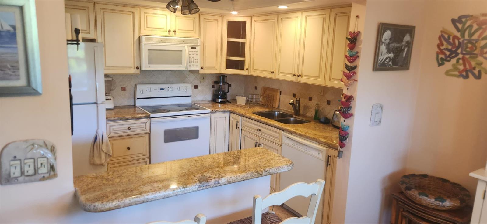A kitchen with cream cabinets, granite countertops, white appliances, and a breakfast bar — 5510 N Ocean # 206, Ocean Ridge FL 33435, OCEAN RIDGE, FL