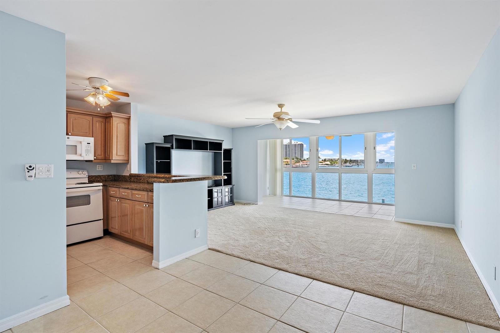 A kitchen with wood cabinets and a living area with carpet overlook a water view — 400 Wilma Circle # 206, Riviera Beach FL 33404, RIVIERA BEACH, FL