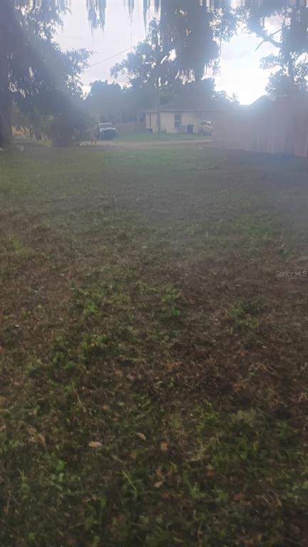 A grassy, partially shaded vacant lot viewed from a low angle toward a distant house — 840 S HIGHLAND AVENUE, APOPKA, FL