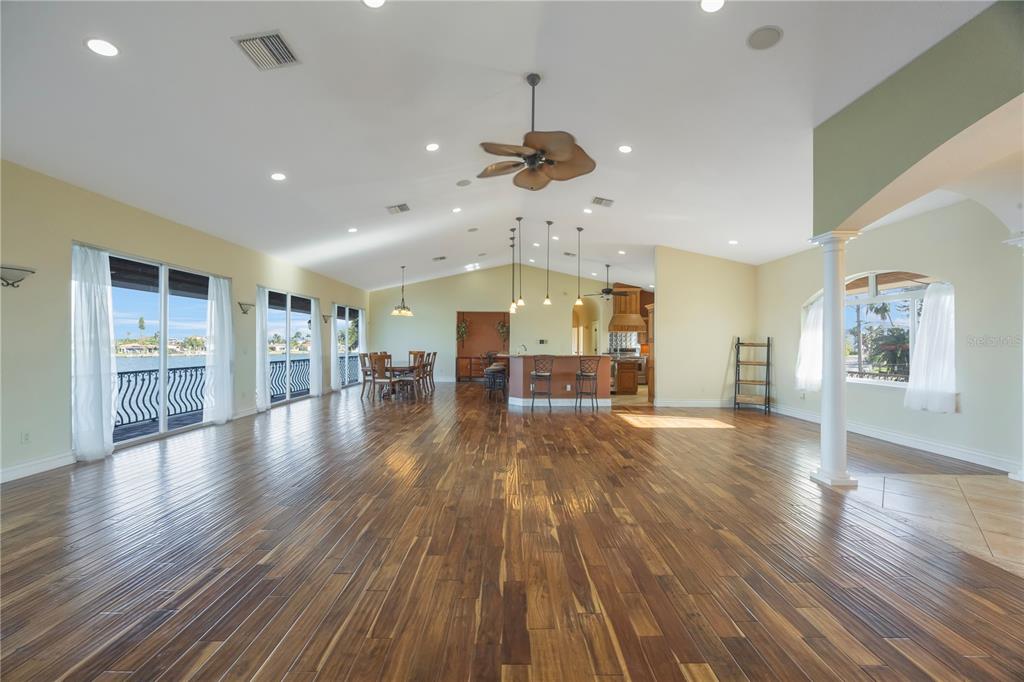 A spacious open-concept living area features hardwood floors, a vaulted ceiling, and waterfront views — 736 PRUITT DRIVE, MADEIRA BEACH, FL
