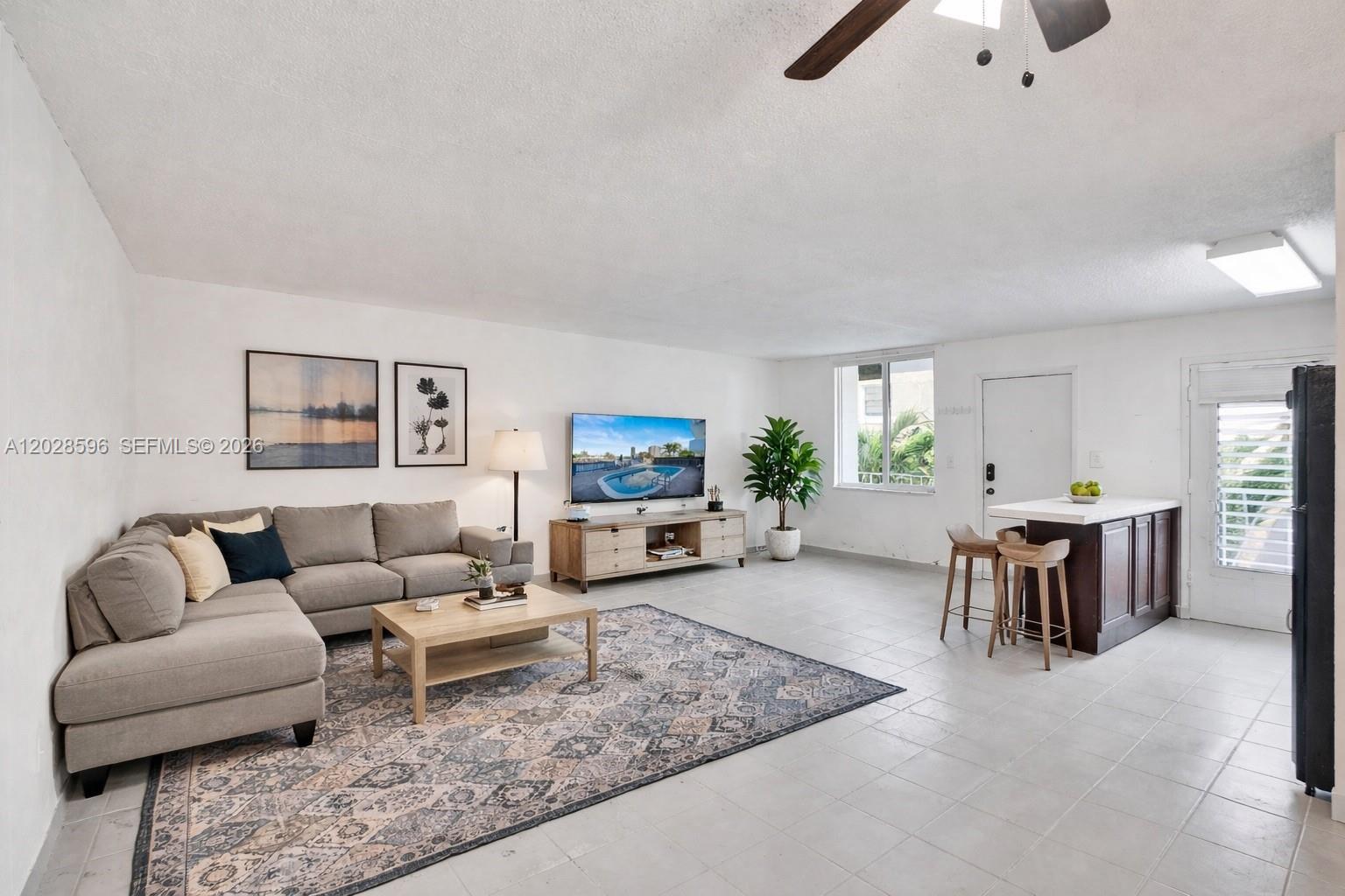 A living room features a gray sectional sofa, a patterned rug, and a kitchen island — 7133 Bay Dr # 305, Miami Beach FL 33141, MIAMI BEACH, FL