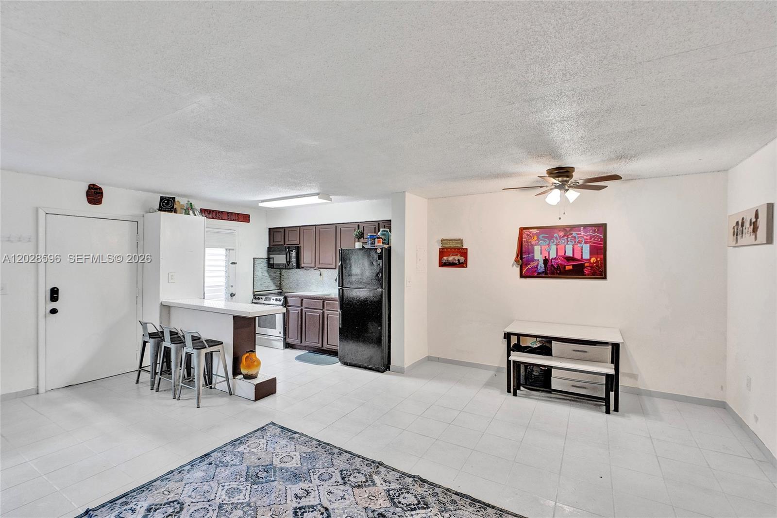 This kitchen and dining area features white tile flooring, dark cabinetry, and a breakfast bar — 7133 Bay Dr # 305, Miami Beach FL 33141, MIAMI BEACH, FL