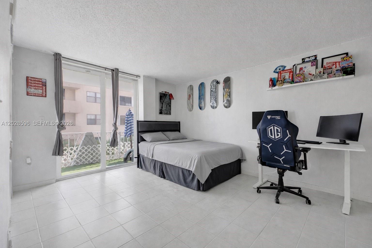 A bedroom features a bed, a gaming desk with a chair, and skateboard wall decor — 7133 Bay Dr # 305, Miami Beach FL 33141, MIAMI BEACH, FL