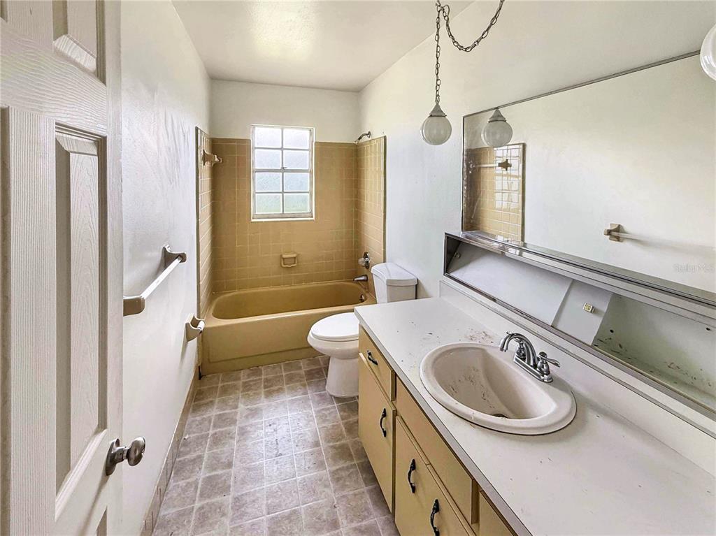 A bathroom features a vanity with a sink, a toilet, and a tiled tub-shower combination — 590 BELLTOWER AVENUE UNIT H, DELTONA, FL