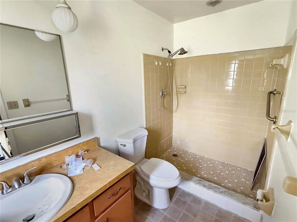 A bathroom features a vanity, a toilet, and a walk-in shower with tan tile walls — 590 BELLTOWER AVENUE UNIT H, DELTONA, FL