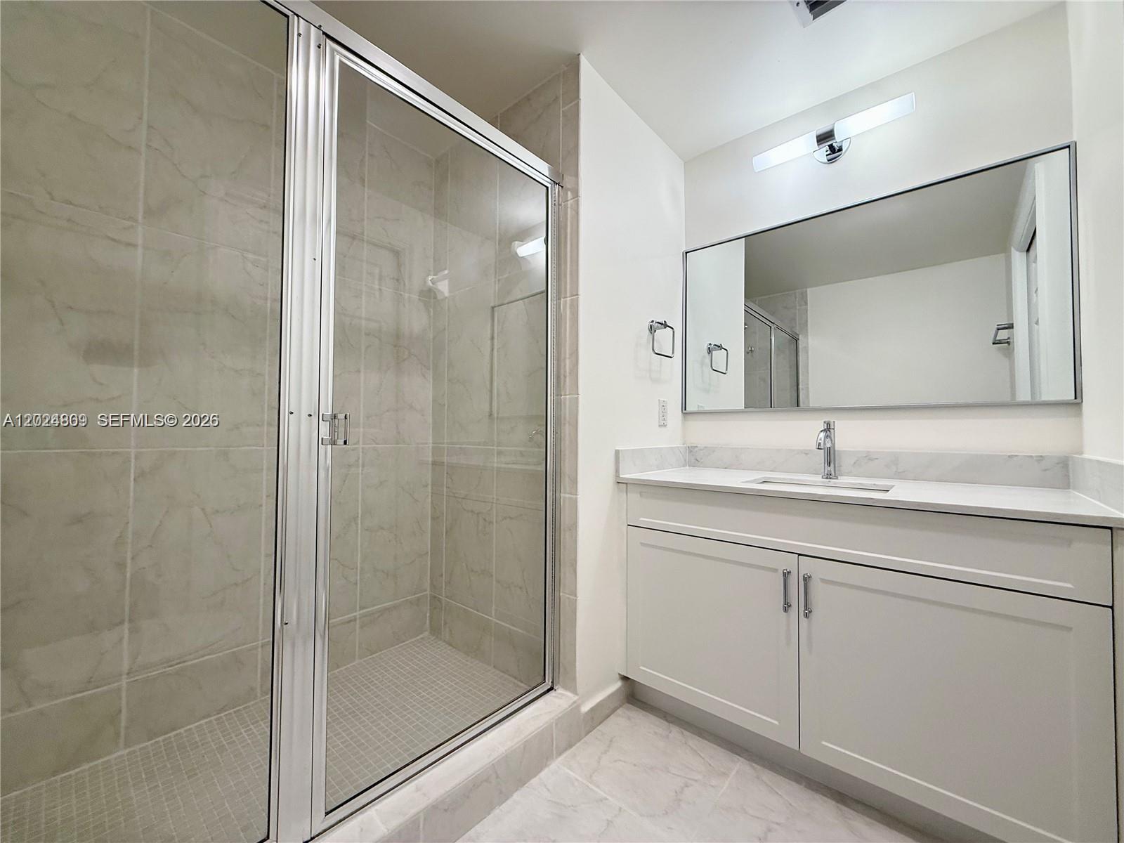 A bathroom features a glass-enclosed shower, a white vanity with a mirror, and tiled flooring — 6851 SW 44th St # 207, Miami FL 33155, MIAMI, FL