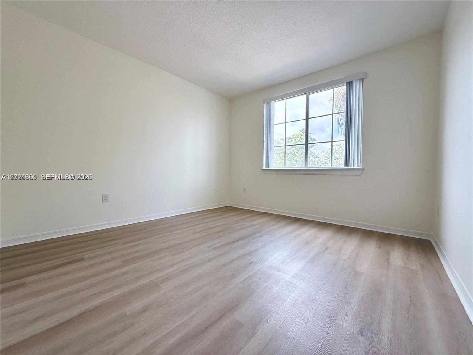 An empty bedroom features light-colored wood-look flooring, white walls, and a single window — 6851 SW 44th St # 207, Miami FL 33155, MIAMI, FL