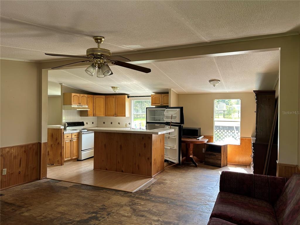 A kitchen with wood cabinets and a breakfast bar opens into a living area — 2751 SE STATE ROAD 121, MORRISTON, FL