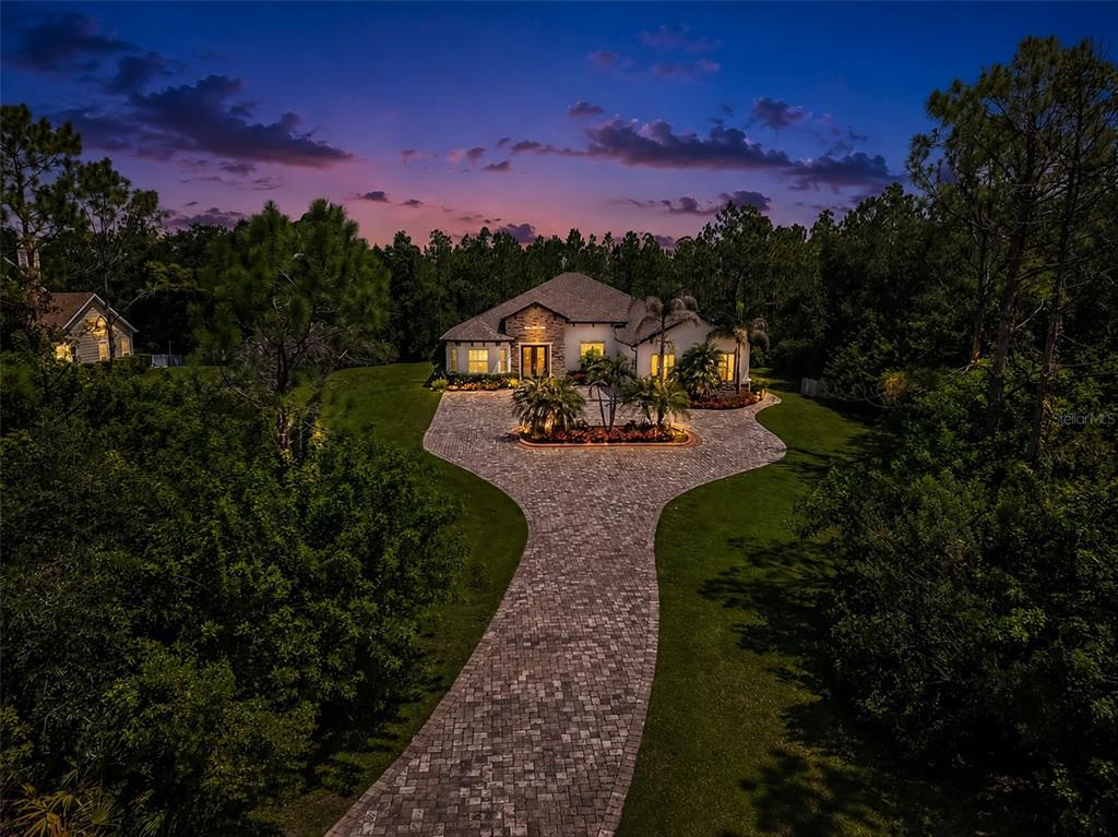 An aerial view of a single-story house with a paved circular driveway at dusk — 22209 DEER POINTE CROSSING, BRADENTON, FL