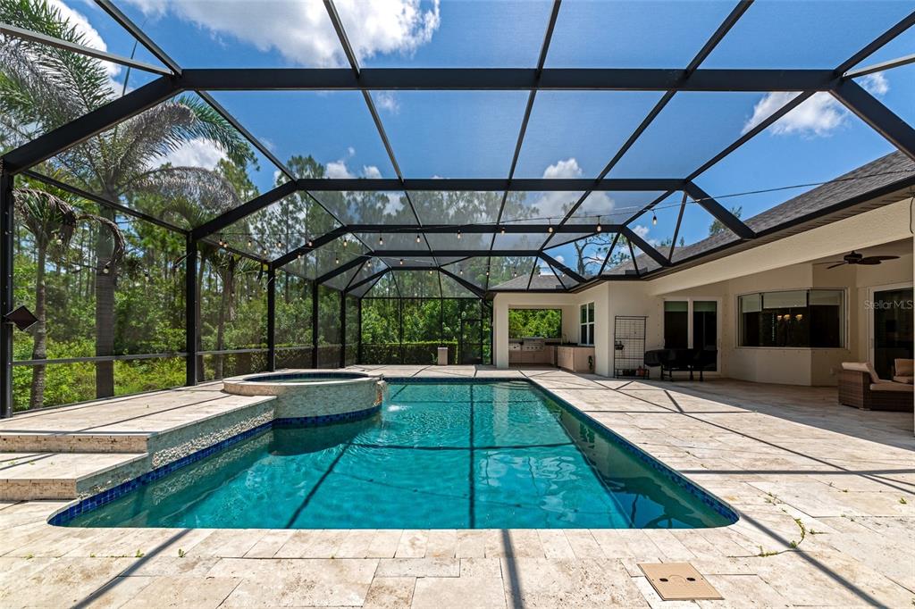 A screened-in patio features a swimming pool with an attached spa and stone decking — 22209 DEER POINTE CROSSING, BRADENTON, FL