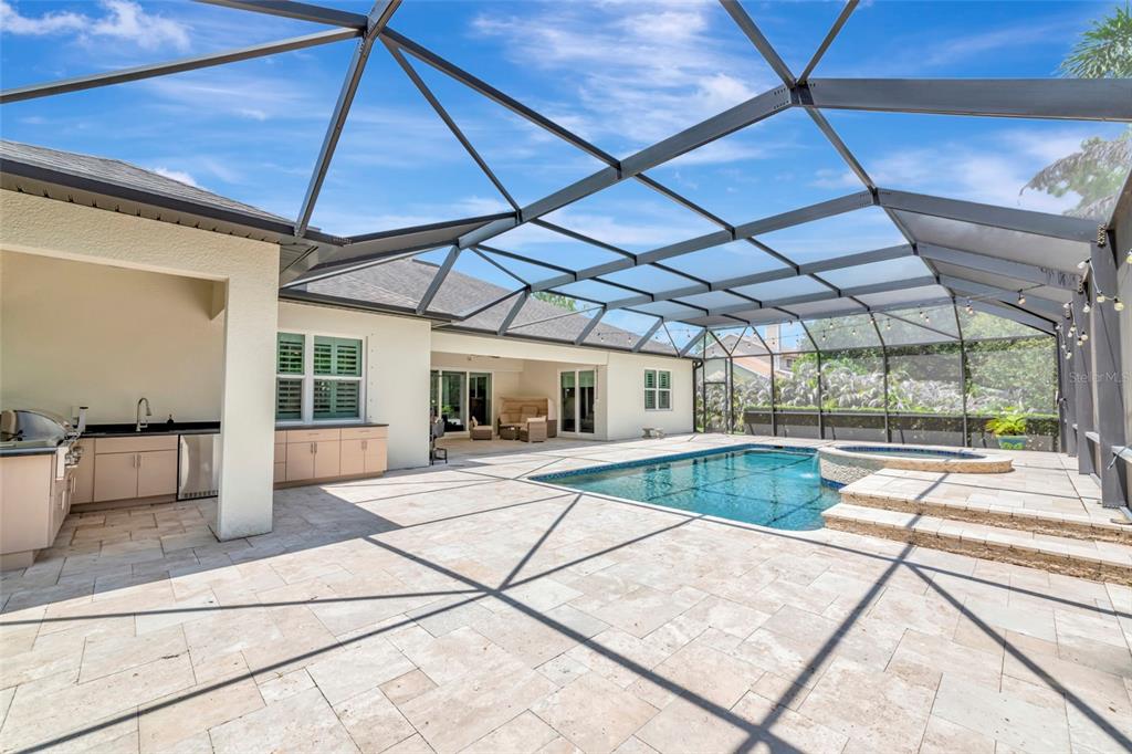 A screened-in patio features a swimming pool, a hot tub, and an outdoor kitchen area — 22209 DEER POINTE CROSSING, BRADENTON, FL