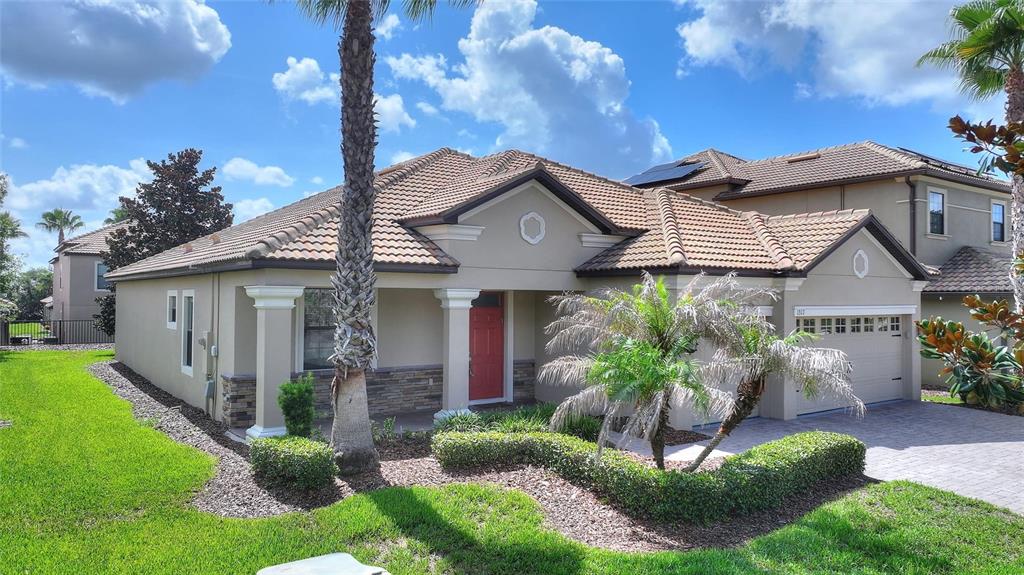 A single-story house with a tiled roof, red front door, and a paved driveway — 1317 GLENEAGLES LN, DAVENPORT, FL