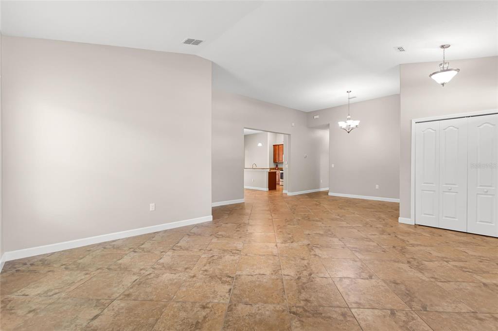 A spacious room with light-colored walls, tiled flooring, a chandelier, and white closet doors — 1317 GLENEAGLES LN, DAVENPORT, FL