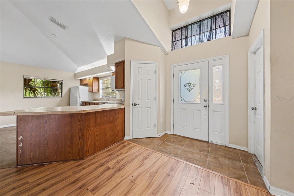 An entryway with tile flooring leads to a kitchen featuring wood cabinets and a counter — 4750 ABACO DRIVE, TAVARES, FL
