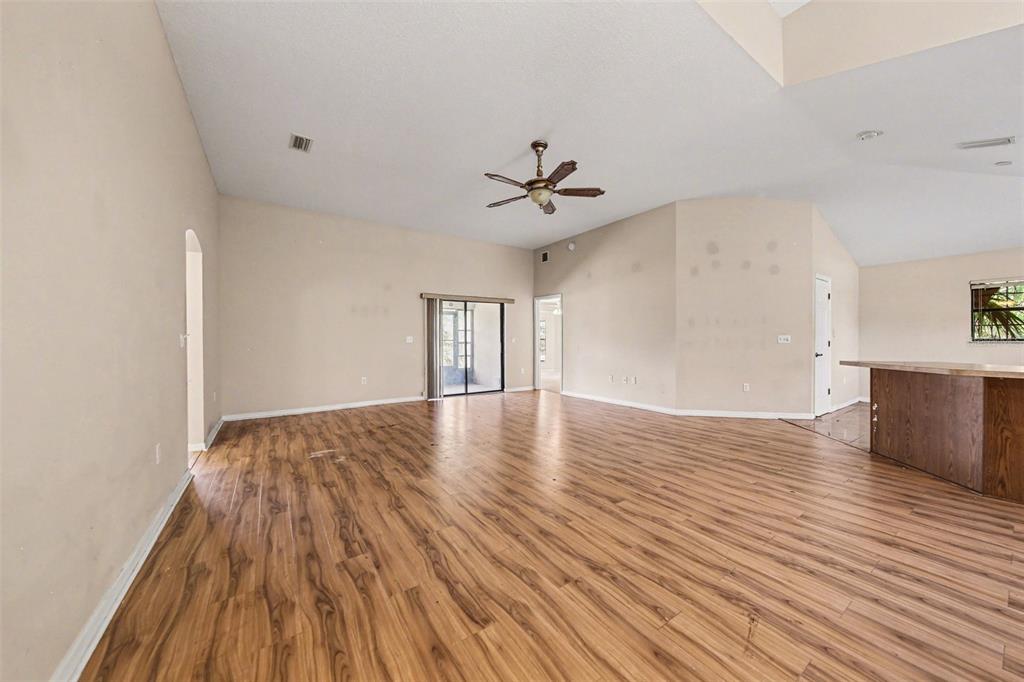 A spacious living room features wood-look flooring, vaulted ceilings, a ceiling fan, and sliding doors — 4750 ABACO DRIVE, TAVARES, FL