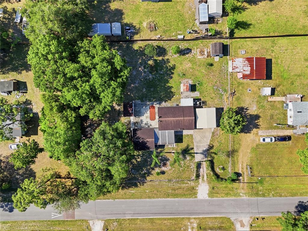 An aerial view shows a house with a metal roof, outbuildings, and mature trees — 17753 EVANS TRAIL, ORLANDO, FL