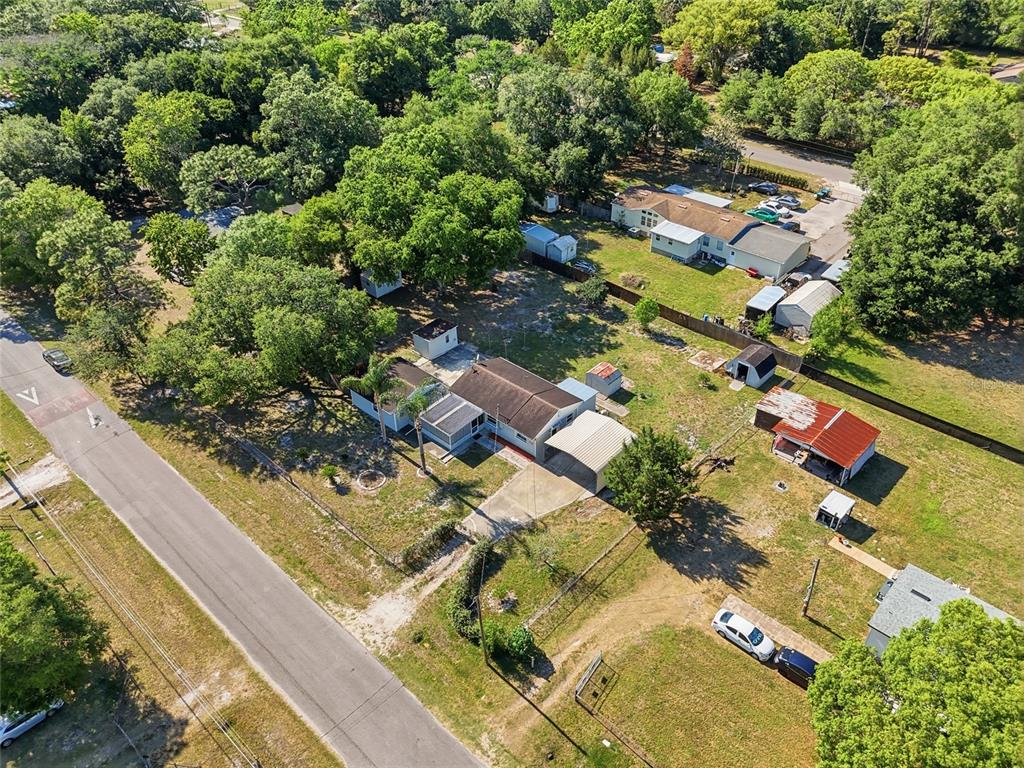 An aerial view shows a single-story house with a carport and several detached storage sheds — 17753 EVANS TRAIL, ORLANDO, FL