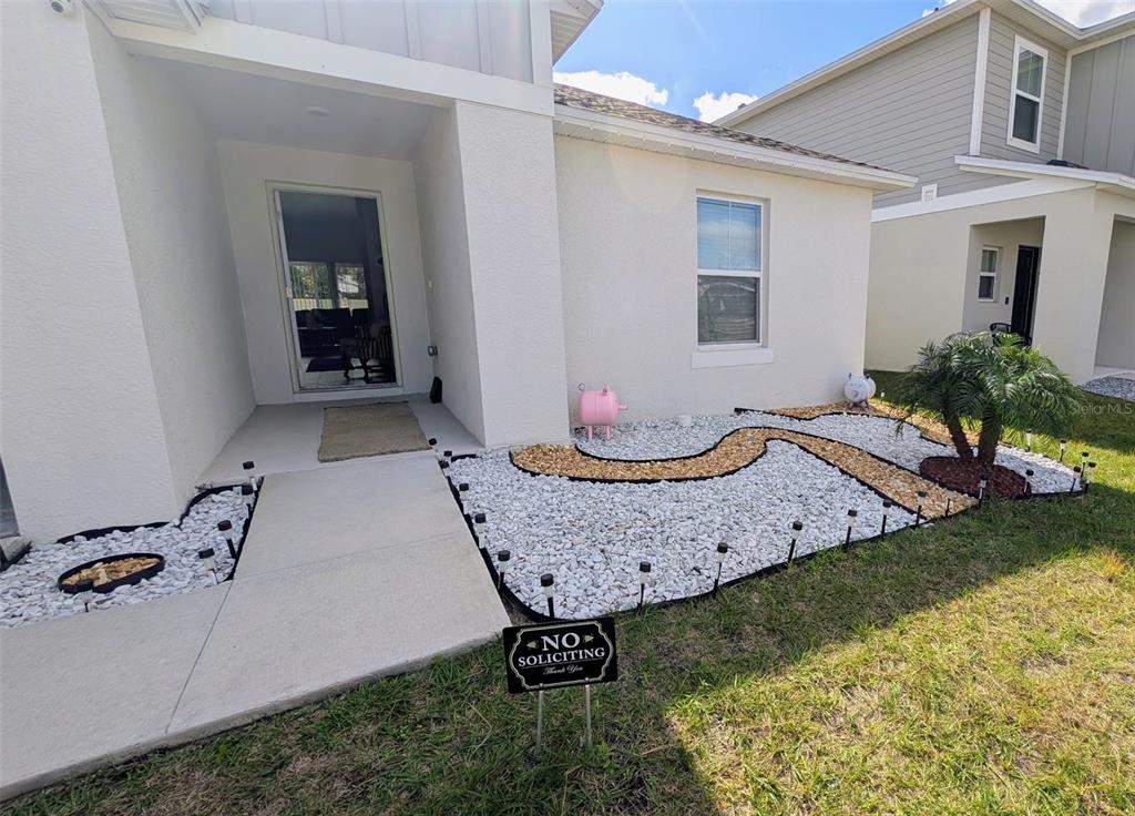 The exterior of a house features a white facade, a rock garden, and a walkway — 5365 MADDIE DRIVE, HAINES CITY, FL