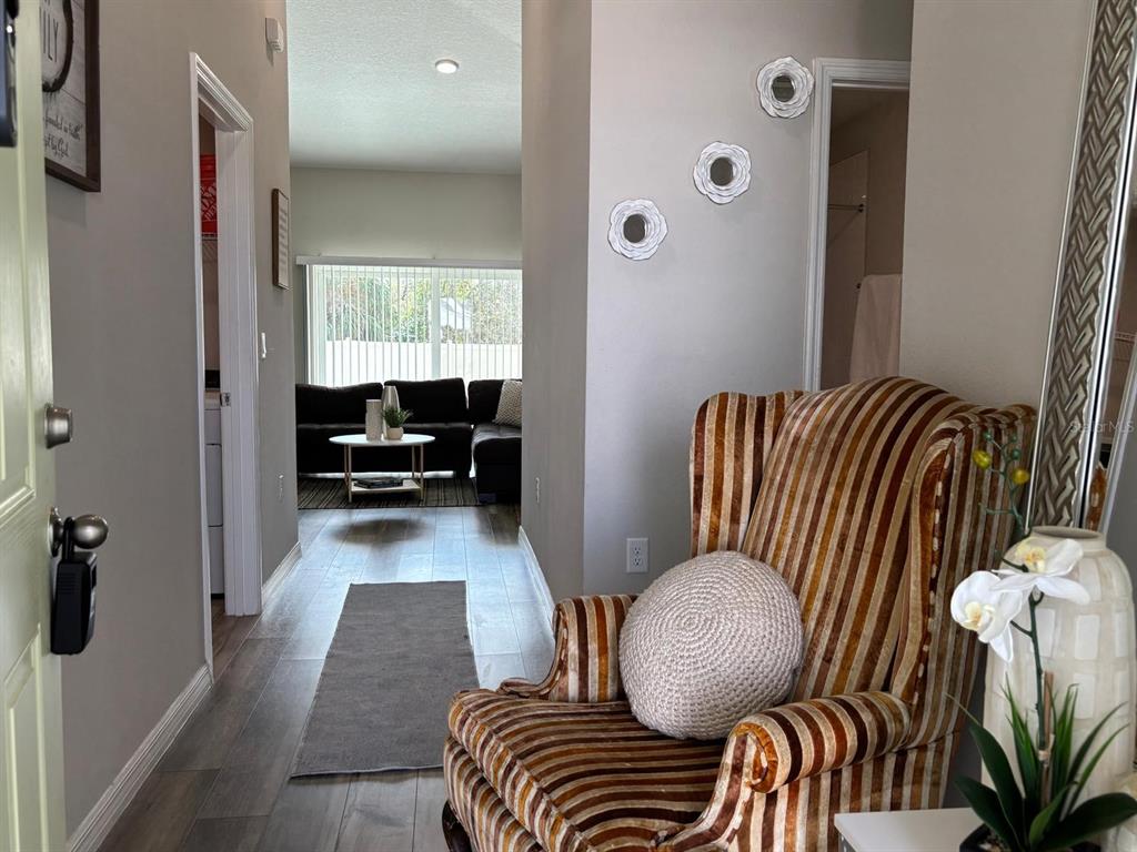 A striped armchair sits in a hallway leading to a living room with a sofa — 5365 MADDIE DRIVE, HAINES CITY, FL