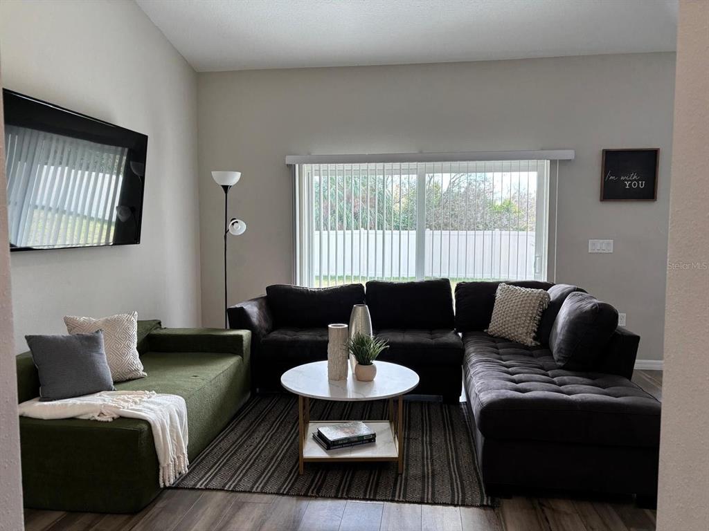 A living room features a green sofa, a dark sectional, and a round coffee table — 5365 MADDIE DRIVE, HAINES CITY, FL