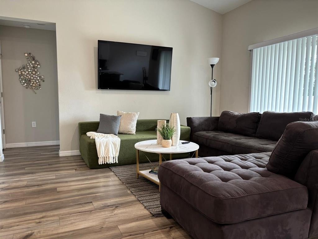 A living room features a green sofa, a dark sectional, and a wall-mounted television — 5365 MADDIE DRIVE, HAINES CITY, FL
