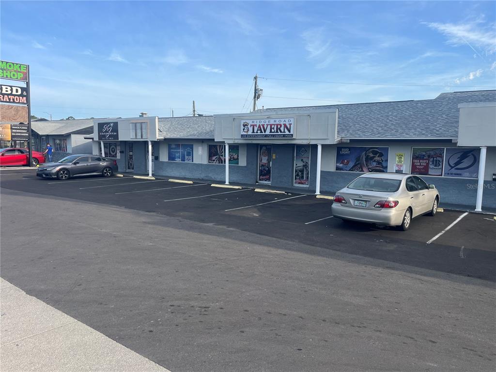 An exterior view of a commercial strip mall featuring a tavern and parking lot — 6201 RIDGE ROAD, PORT RICHEY, FL