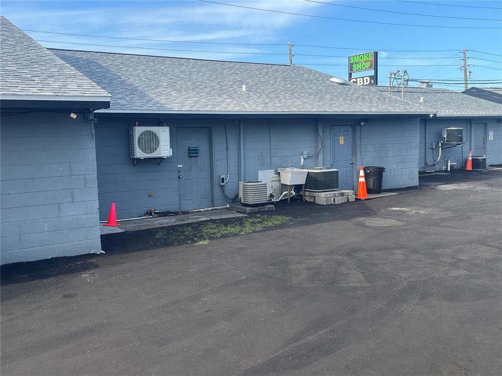 The exterior rear view of a commercial building features gray siding, multiple doors, and HVAC units — 6201 RIDGE ROAD, PORT RICHEY, FL