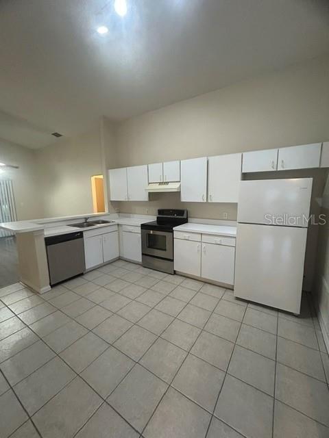 A kitchen features white cabinets, a white refrigerator, a stainless steel stove, and tiled flooring — 816 SHELL LANE, LONGWOOD, FL