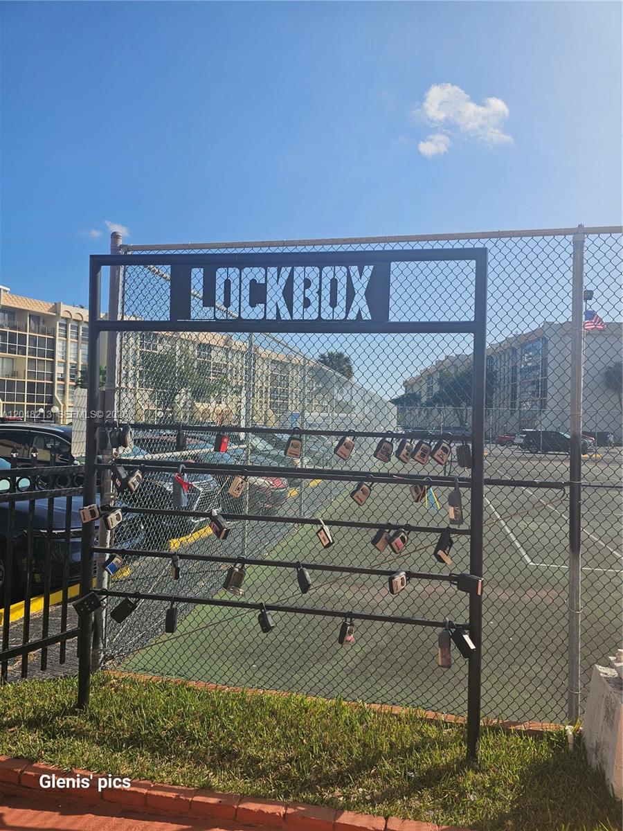 A metal rack labeled "LOCKBOX" holds numerous real estate lockboxes attached to a chain-link fence — 801 Three Islands Blvd # 218, Hallandale Beach FL 33009, HALLANDALE BEACH, FL