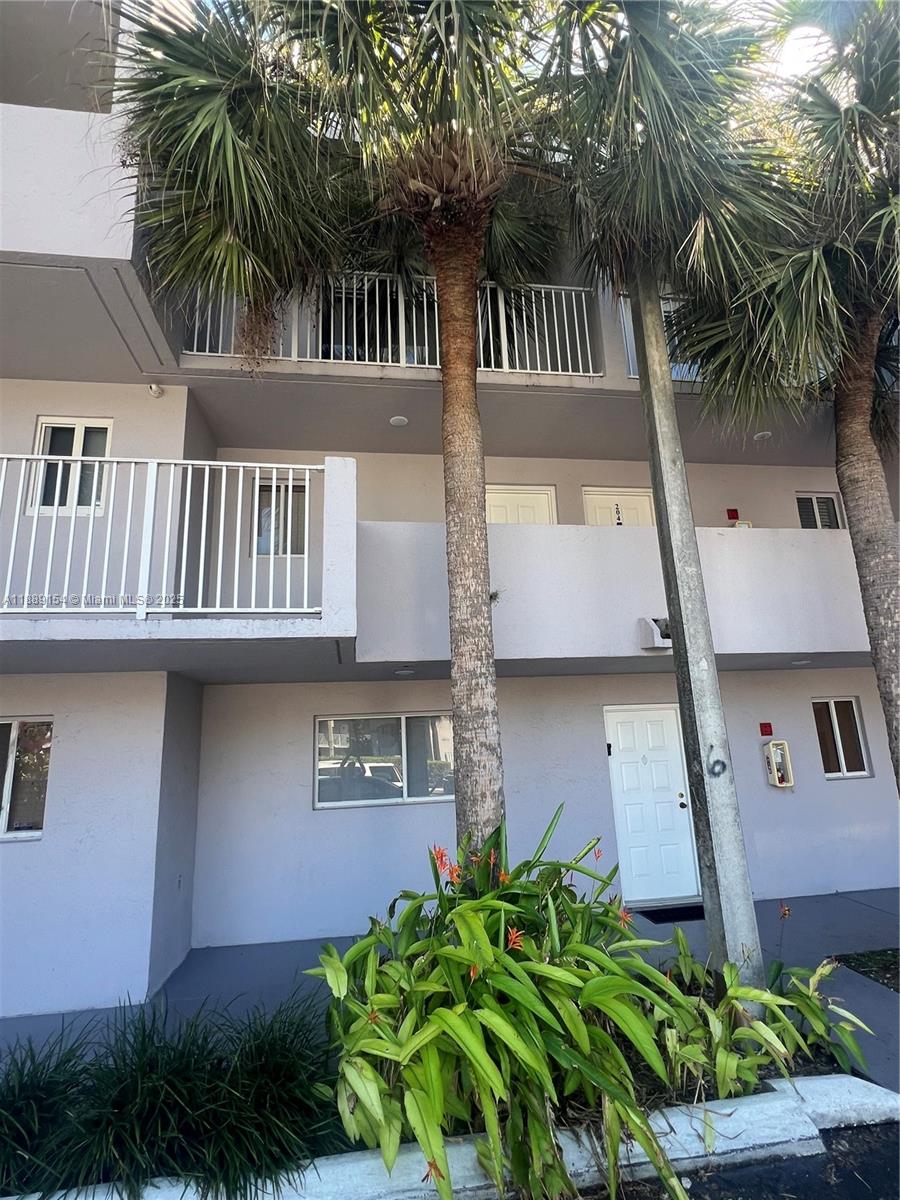 The exterior of a multi-story apartment building features palm trees and a ground-level entrance — 2750 W 76th St # 203, Hialeah FL 33016, HIALEAH, FL