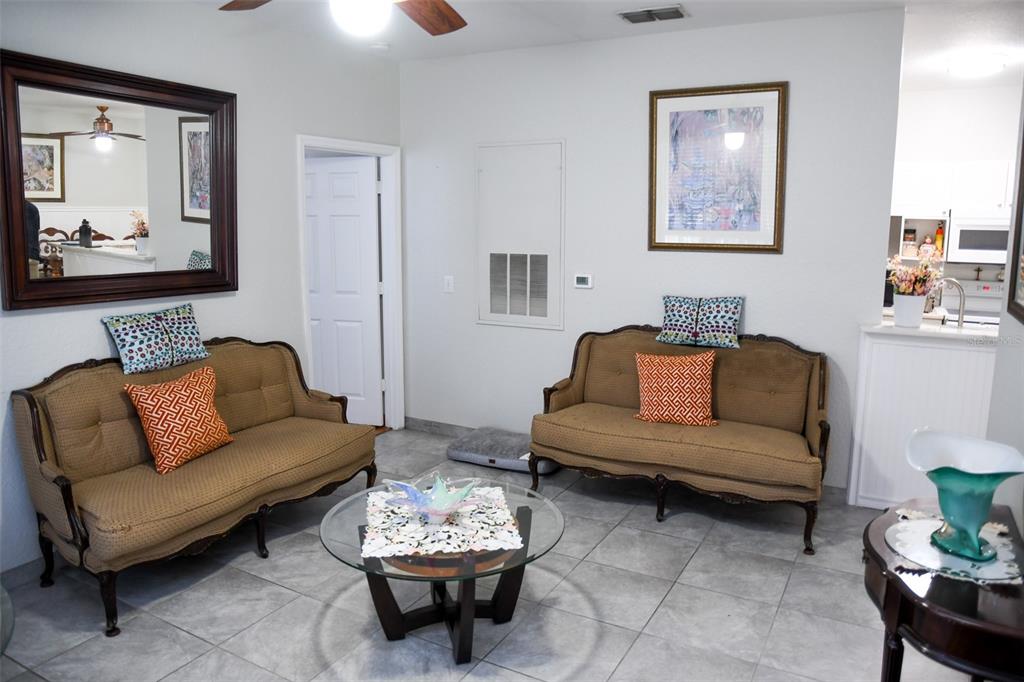 A living room features two tan sofas, a glass coffee table, and tile flooring — 830 GRAND REGENCY POINT UNIT 101, ALTAMONTE SPRINGS, FL