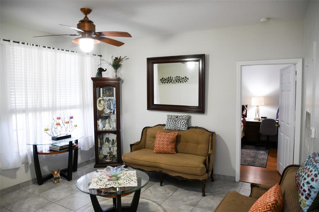 A living room features a tan settee, a glass coffee table, and a display cabinet — 830 GRAND REGENCY POINT UNIT 101, ALTAMONTE SPRINGS, FL